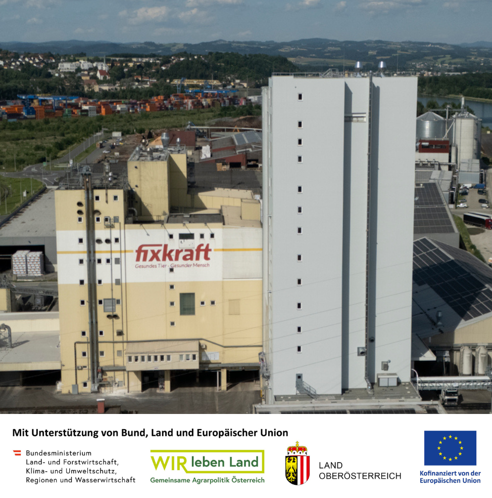 A large industrial facility with a beige 'fixkraft' building and tall gray silos, set in a factory complex.